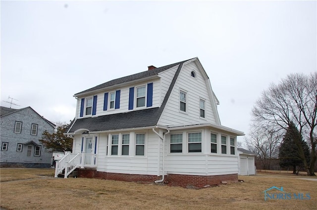 colonial inspired home featuring a shingled roof, a chimney, a front lawn, and a gambrel roof