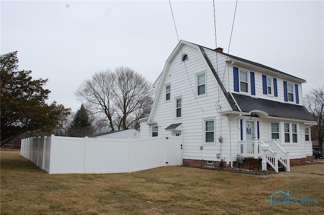 view of side of property featuring a yard, fence, a shingled roof, and a gambrel roof