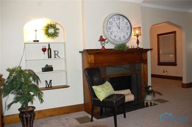 living area featuring carpet floors, a fireplace with flush hearth, visible vents, baseboards, and crown molding