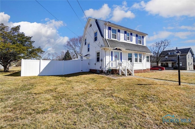 view of front facade featuring a gambrel roof, a shingled roof, a front lawn, and fence