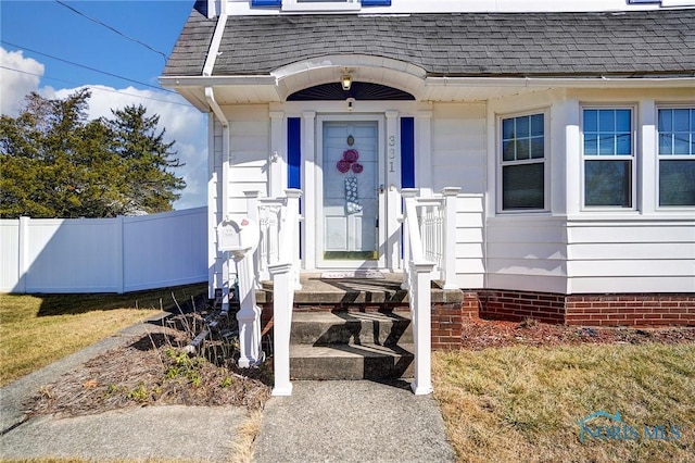 entrance to property featuring fence and a shingled roof