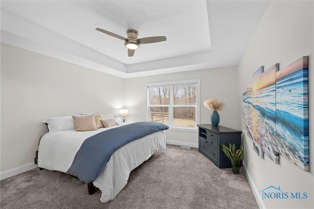 bedroom with baseboards, a tray ceiling, a ceiling fan, and light colored carpet