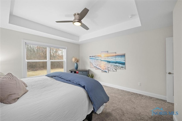 bedroom with carpet flooring, a raised ceiling, a ceiling fan, and baseboards