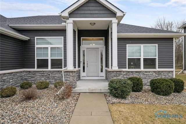 property entrance featuring stone siding and a shingled roof