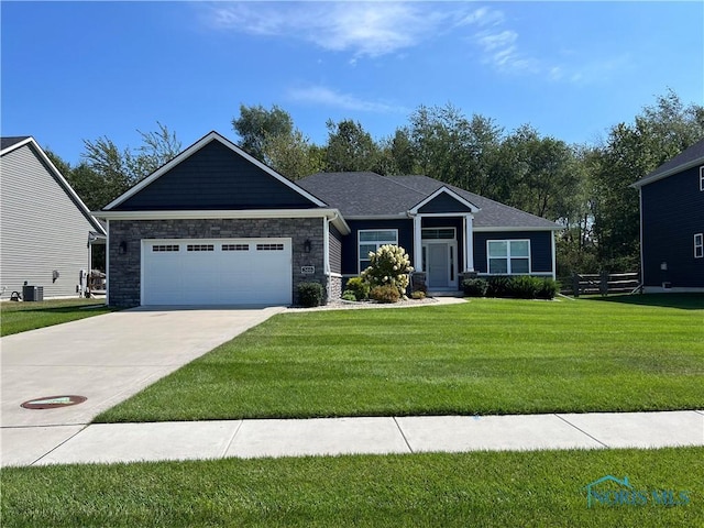 view of front of home with driveway, a front lawn, an attached garage, and stone siding