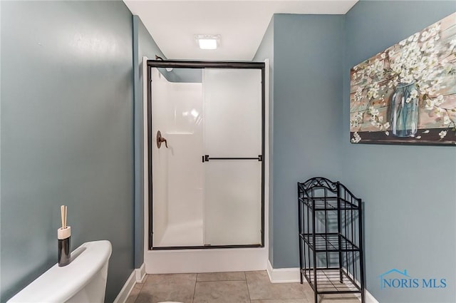 bathroom featuring baseboards, a stall shower, and tile patterned floors