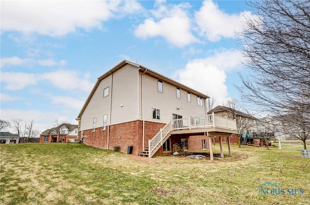 rear view of house featuring a yard, stairs, a deck, and brick siding