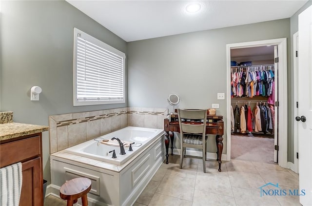 bathroom with a walk in closet, a garden tub, and tile patterned floors