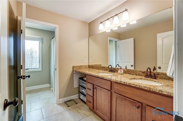 full bathroom featuring baseboards, double vanity, a sink, and tile patterned floors