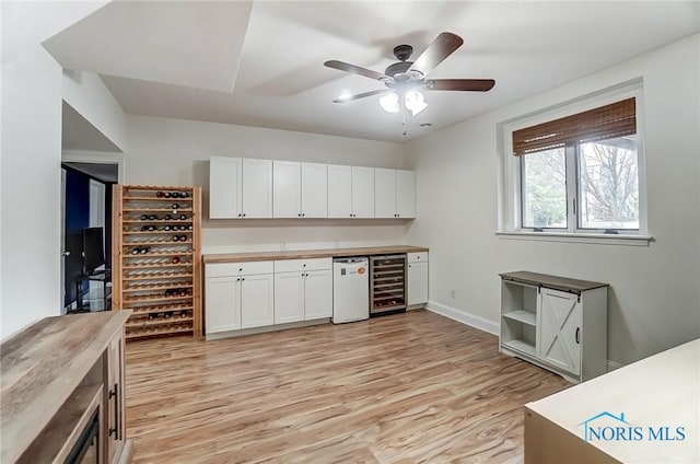 interior space featuring light wood-style flooring, wine cooler, baseboards, and ceiling fan