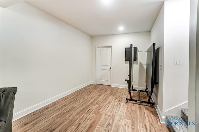 exercise area with light wood finished floors and baseboards