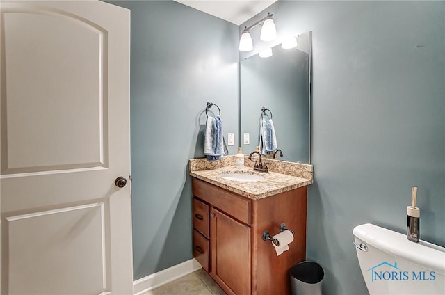 half bath with toilet, tile patterned flooring, baseboards, and vanity