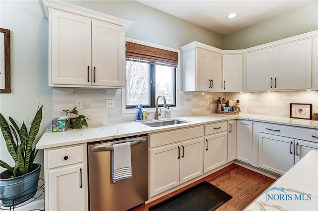 kitchen featuring dark wood-style flooring, decorative backsplash, stainless steel dishwasher, white cabinets, and a sink