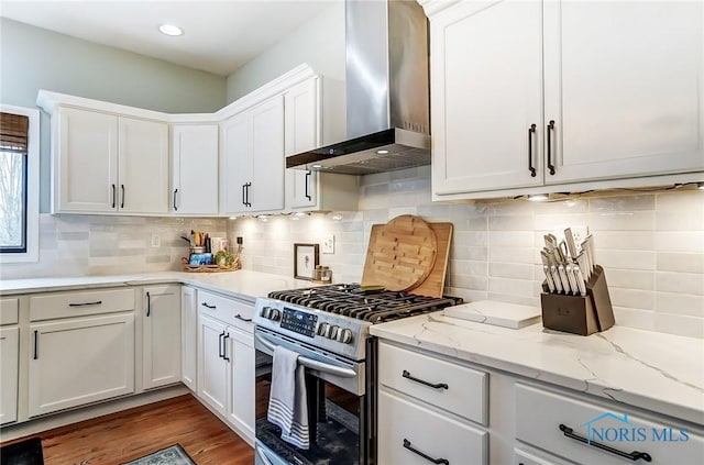 kitchen featuring wall chimney exhaust hood, white cabinets, wood finished floors, and gas stove