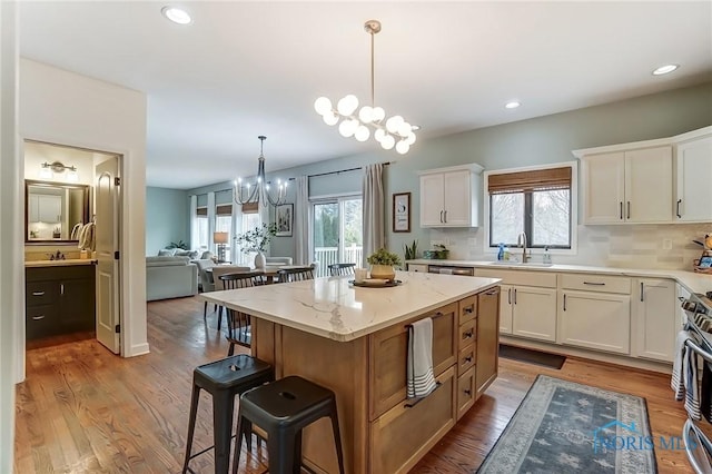 kitchen with an inviting chandelier, a kitchen breakfast bar, wood finished floors, and decorative light fixtures