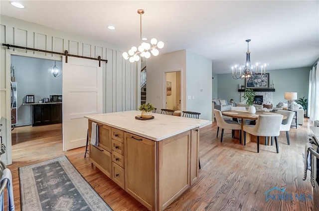 kitchen featuring a center island, a notable chandelier, light wood-style flooring, and a barn door