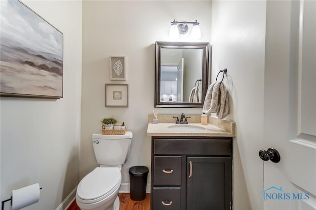 half bathroom featuring baseboards, vanity, and toilet