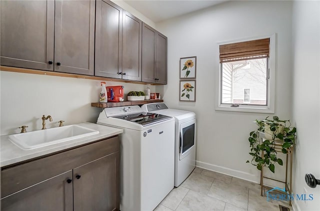 laundry room with light tile patterned floors, a sink, baseboards, cabinet space, and washing machine and clothes dryer