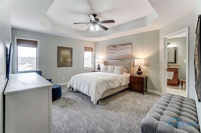 bedroom featuring multiple windows, a raised ceiling, and light colored carpet