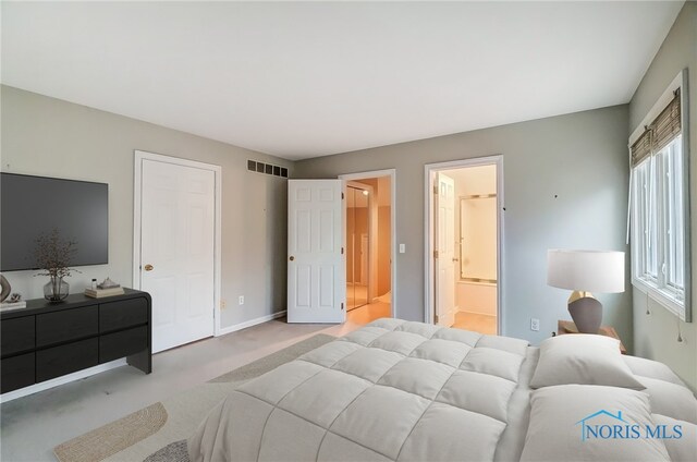 bedroom with light carpet, ensuite bathroom, visible vents, and baseboards