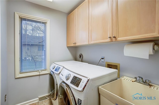 laundry area featuring cabinet space, a sink, baseboards, and separate washer and dryer