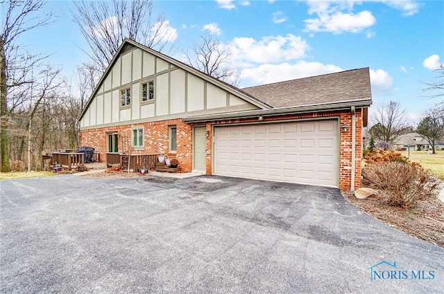 view of front of home with a garage, brick siding, a shingled roof, driveway, and stucco siding