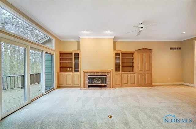 unfurnished living room with a tile fireplace, light colored carpet, crown molding, and baseboards