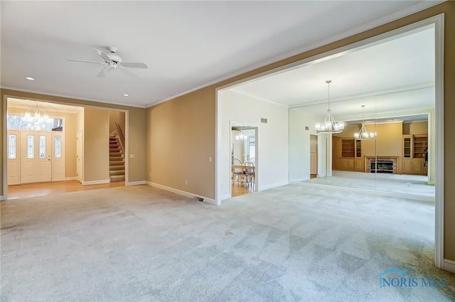 unfurnished living room featuring crown molding, stairway, light carpet, baseboards, and ceiling fan with notable chandelier