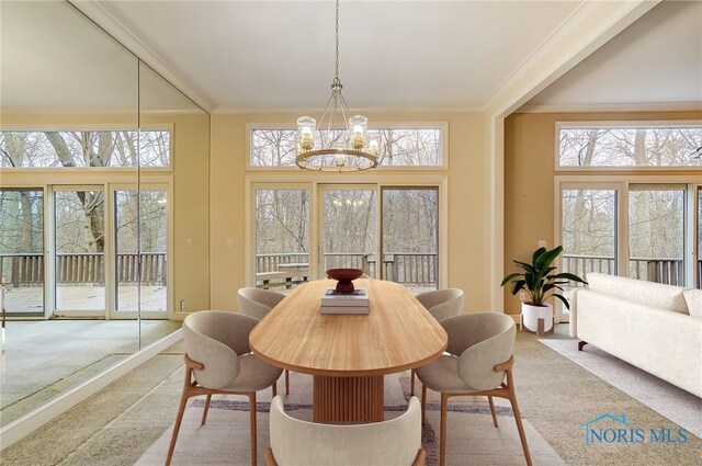 carpeted dining area with ornamental molding, a wealth of natural light, and a notable chandelier