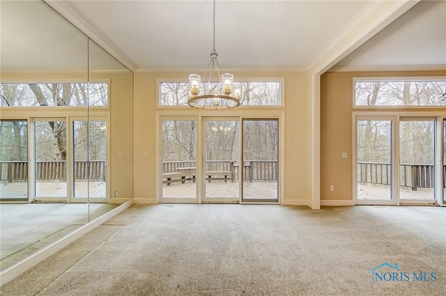 doorway to outside with a notable chandelier, carpet flooring, a wealth of natural light, and baseboards