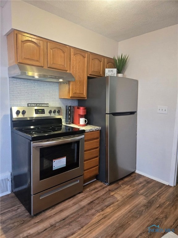 kitchen with under cabinet range hood, dark wood-type flooring, visible vents, appliances with stainless steel finishes, and backsplash