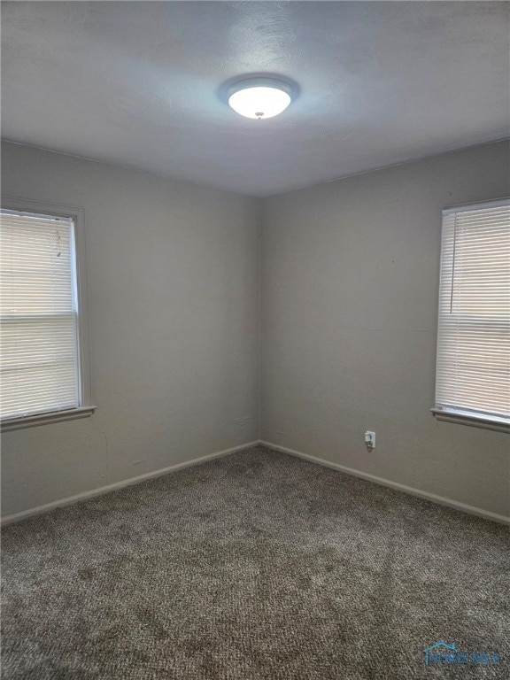 unfurnished room featuring carpet and baseboards