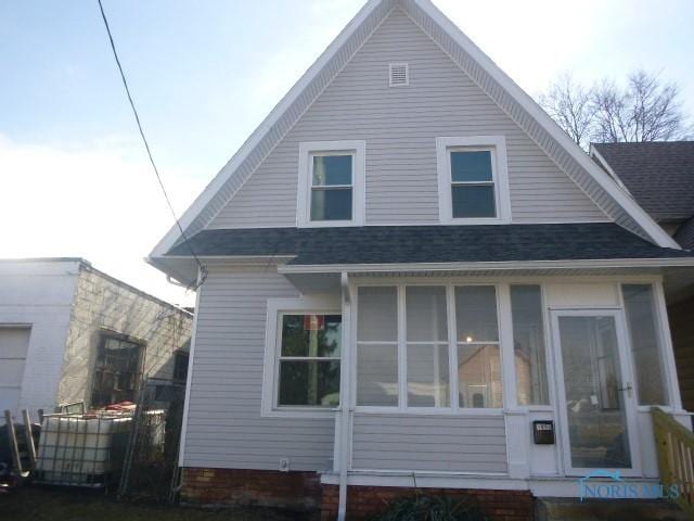 back of property featuring a sunroom and a shingled roof