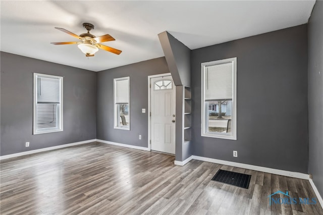interior space featuring visible vents, baseboards, wood finished floors, and a ceiling fan