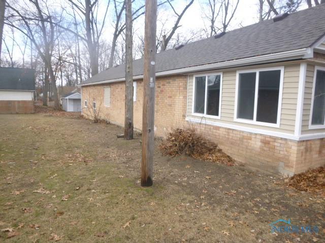 view of side of home featuring a shingled roof and brick siding