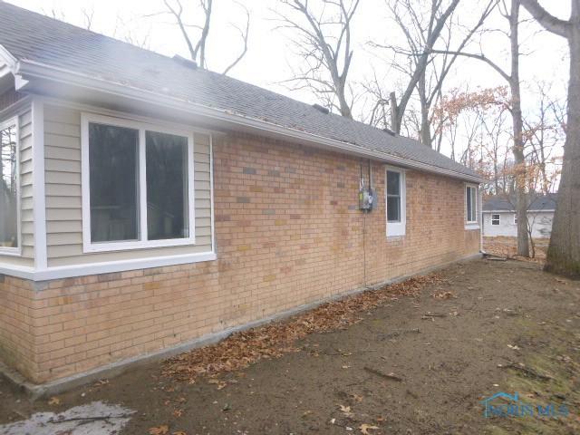 view of side of property with brick siding and roof with shingles