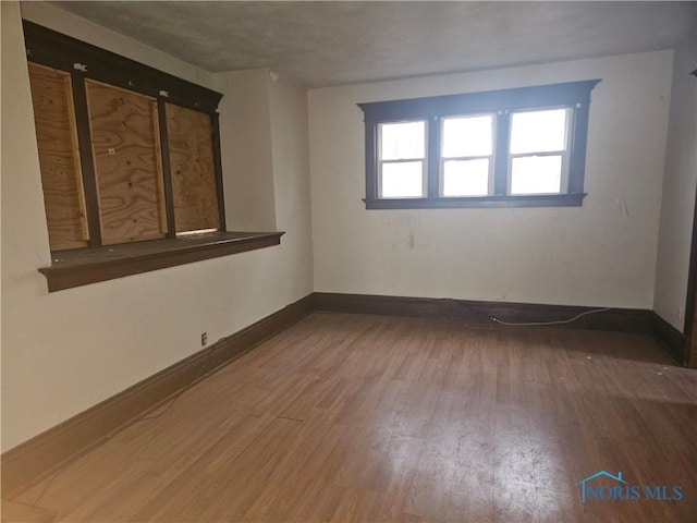 spare room featuring baseboards and wood finished floors