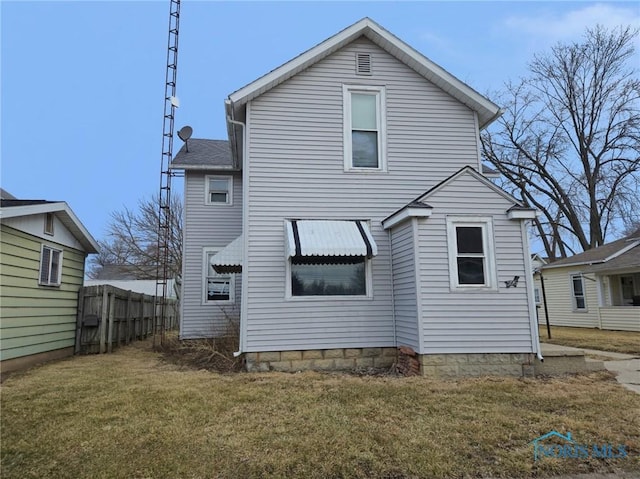 back of house featuring fence and a lawn