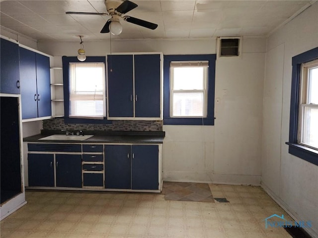 kitchen featuring dark countertops, light floors, blue cabinets, and a sink