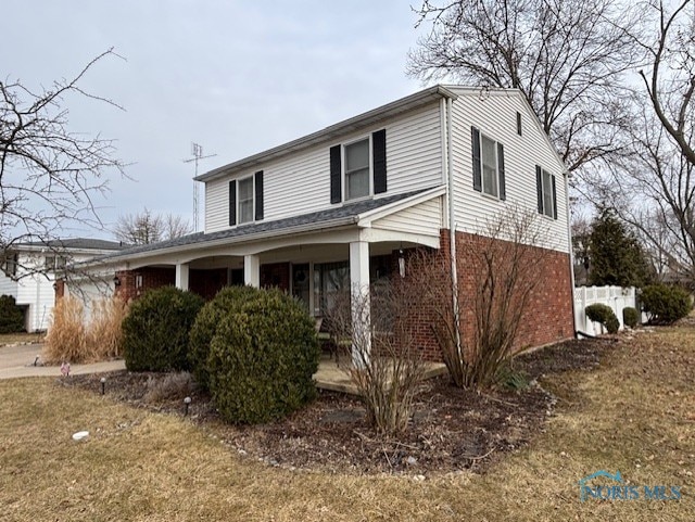 view of side of home with brick siding and a porch