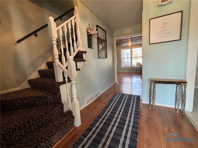 stairs with visible vents, baseboards, and wood finished floors