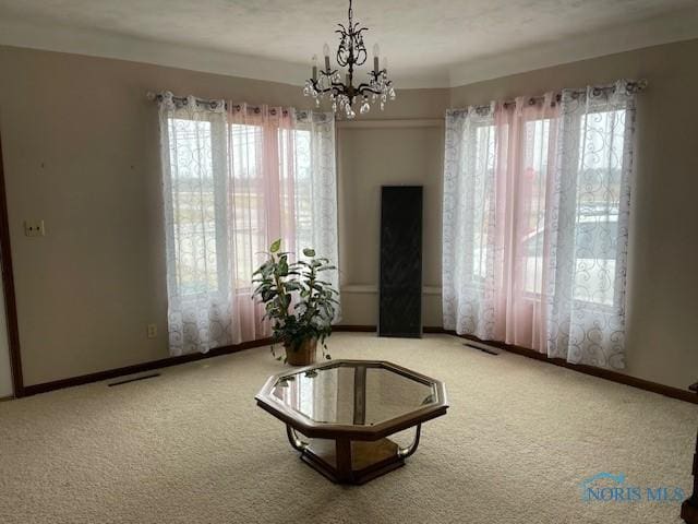 living area with carpet flooring, an inviting chandelier, plenty of natural light, and baseboards