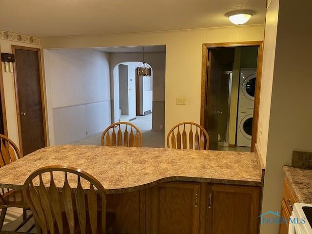 dining space featuring arched walkways and stacked washer / drying machine