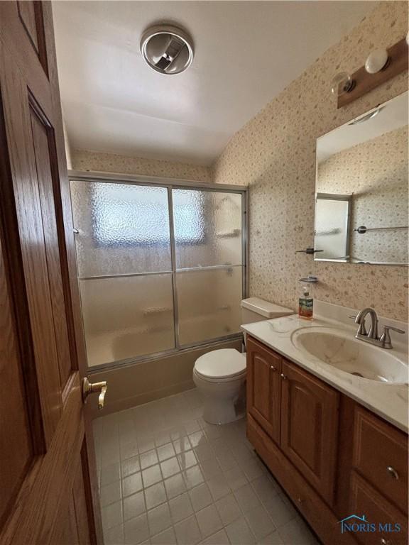 full bath featuring toilet, shower / bath combination with glass door, vanity, tile patterned floors, and wallpapered walls