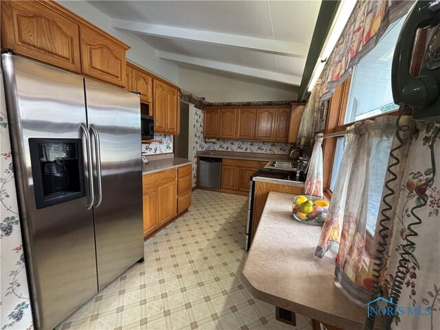 kitchen with lofted ceiling with beams, appliances with stainless steel finishes, brown cabinets, light floors, and a sink