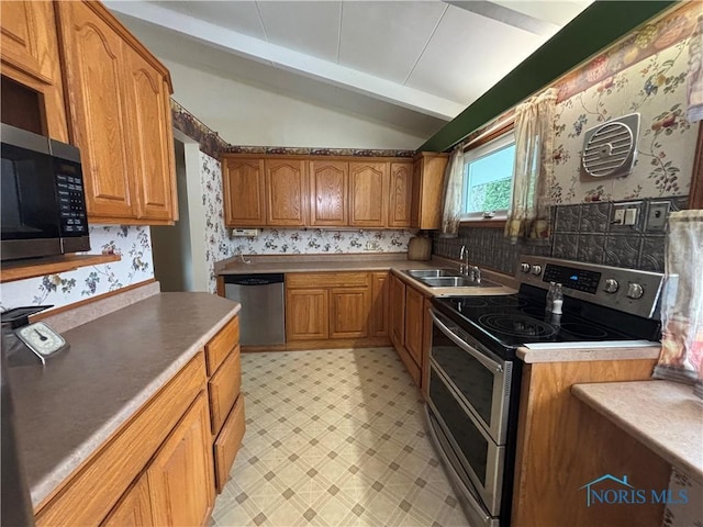 kitchen with vaulted ceiling with beams, light floors, stainless steel appliances, a sink, and wallpapered walls