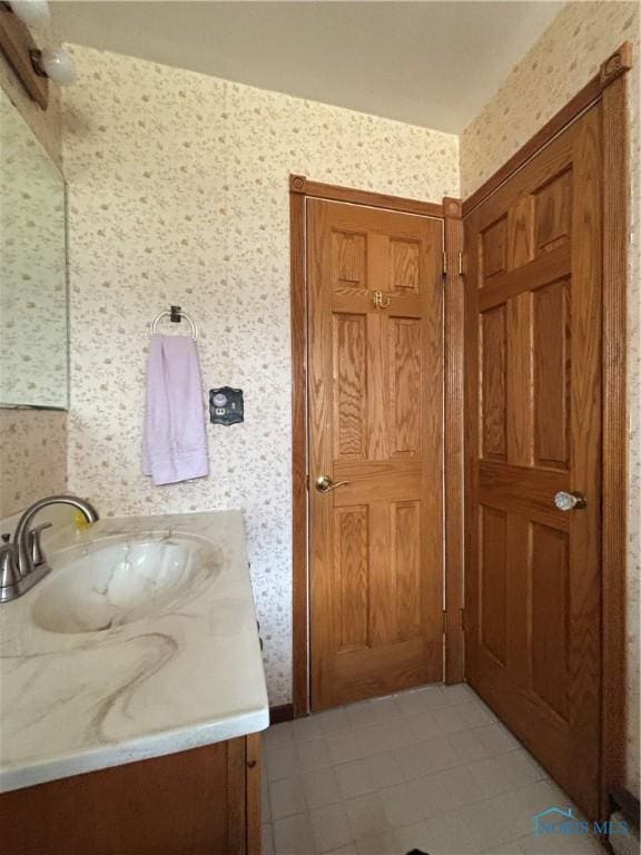 bathroom with vanity and wallpapered walls