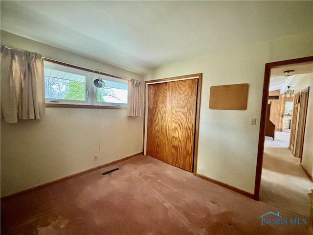 unfurnished bedroom with a closet, carpet, visible vents, and baseboards