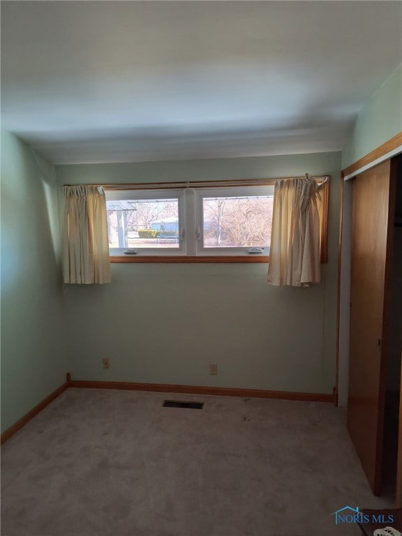 unfurnished bedroom with a closet, visible vents, light carpet, and multiple windows