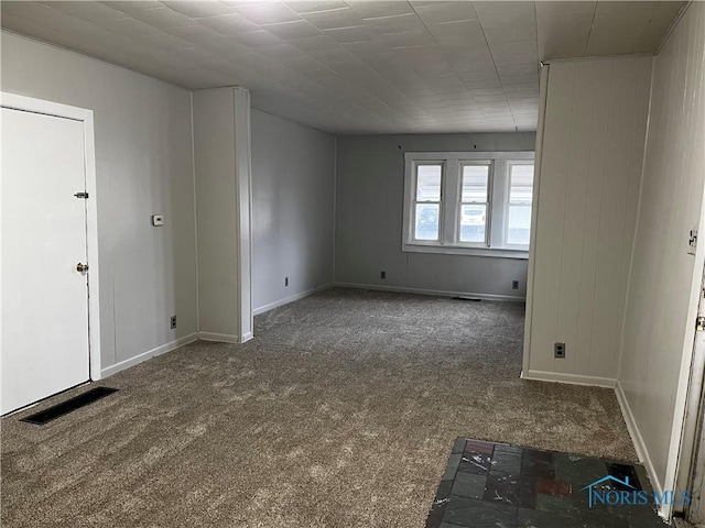 spare room featuring carpet floors, visible vents, and baseboards